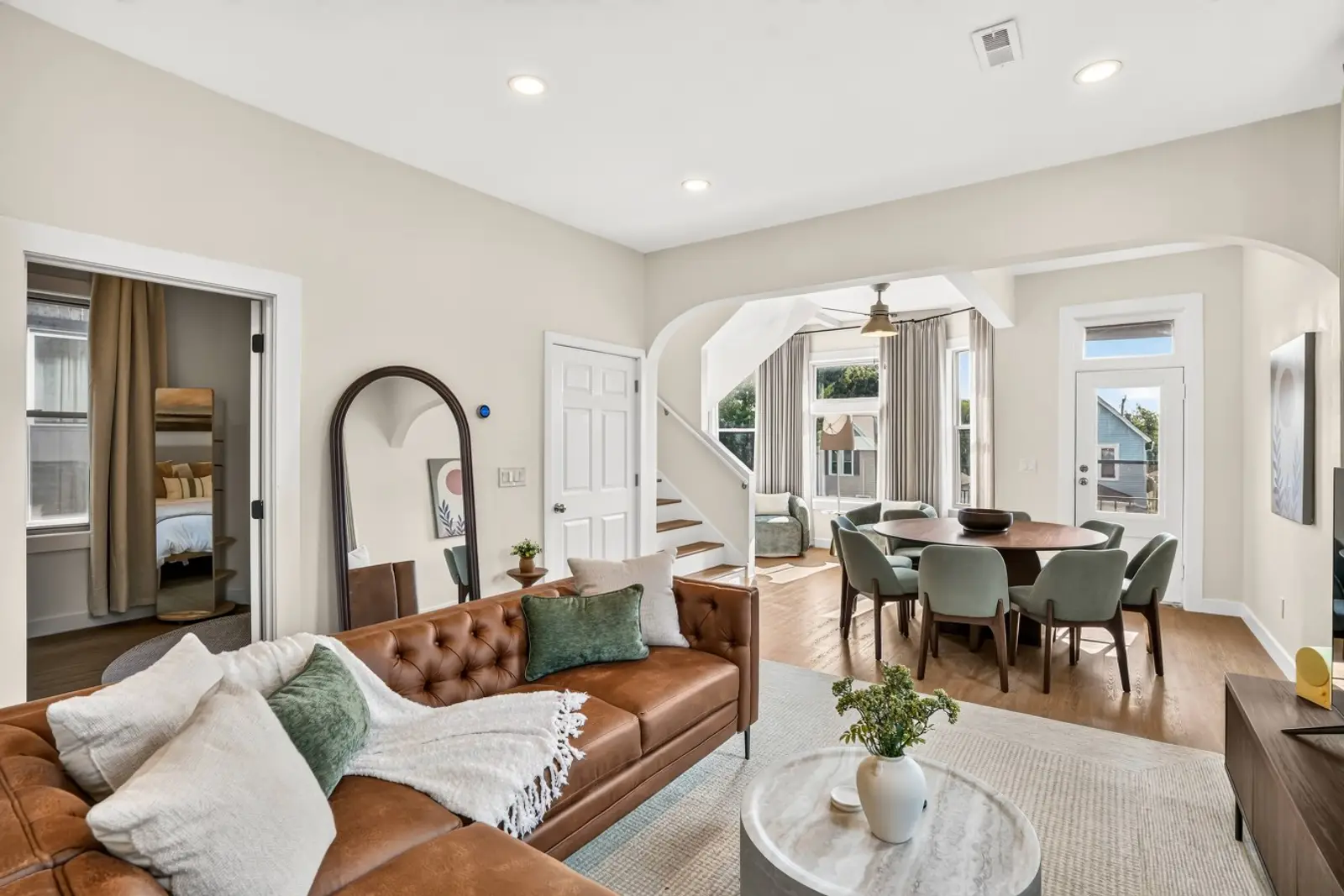 Living room with a leather sofa, opening to the dining table