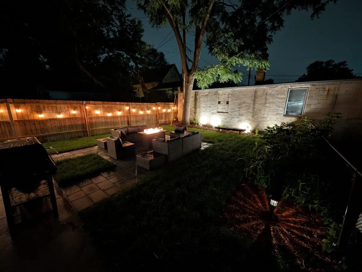Backyard at night with string lights and the fire table lit