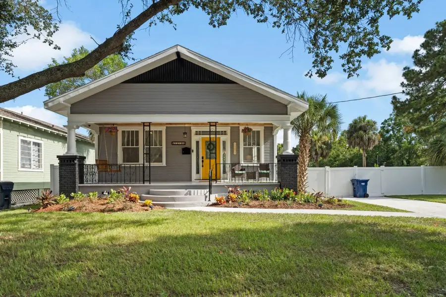 Historic Tampa Bungalow’s front porch, with a yellow door and a porch swing