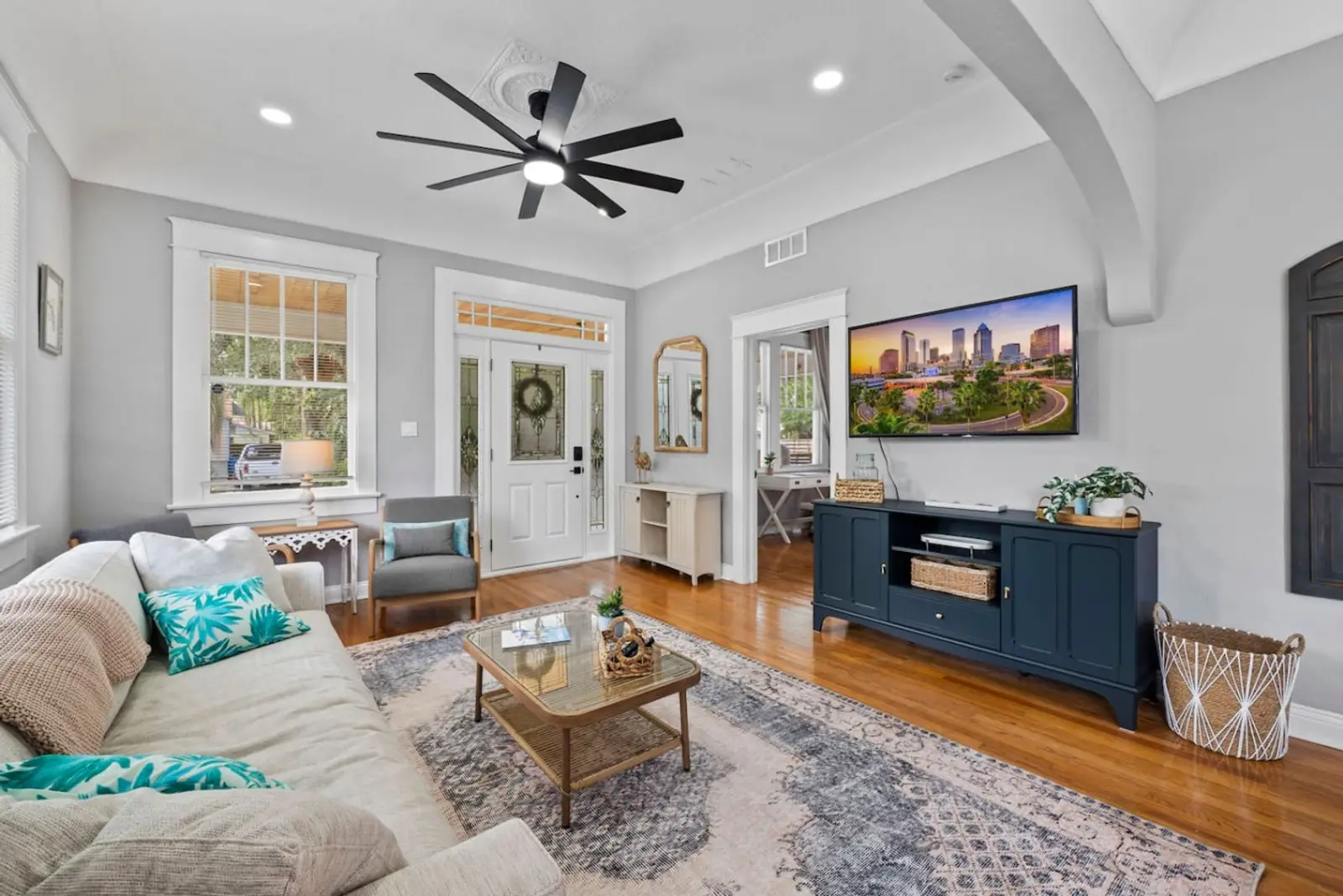 Living room with a cream sofa, a glass coffee table, and a wall-mounted TV