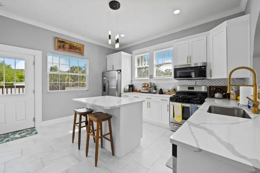 Kitchen island with two stools, a gold faucet, and a door to the back deck