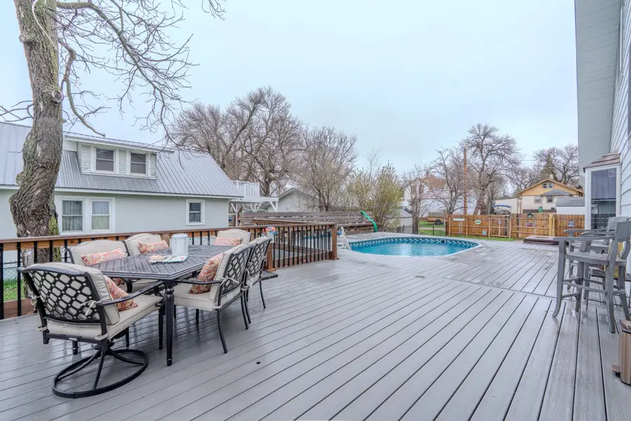 Back deck with an outdoor dining table, a round pool, and a covered hot tub by the fence