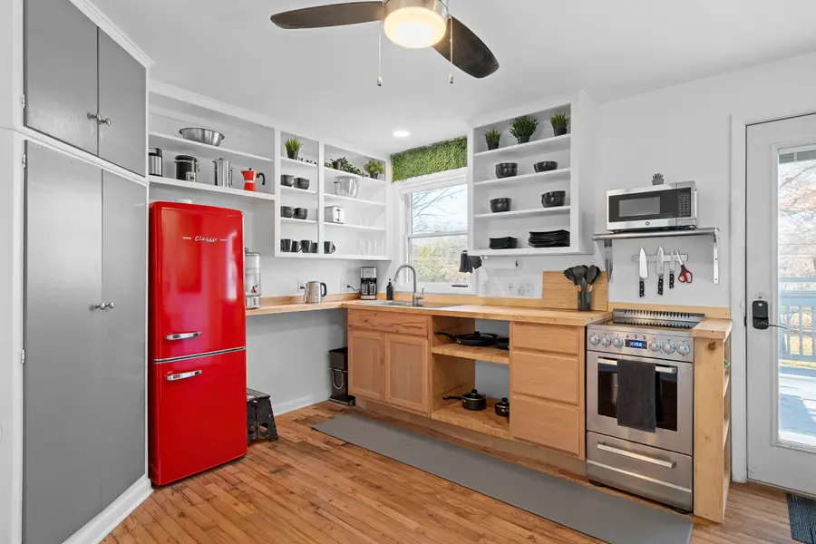 Kitchen with a retro red fridge, open shelving, wood counters, and a stainless range