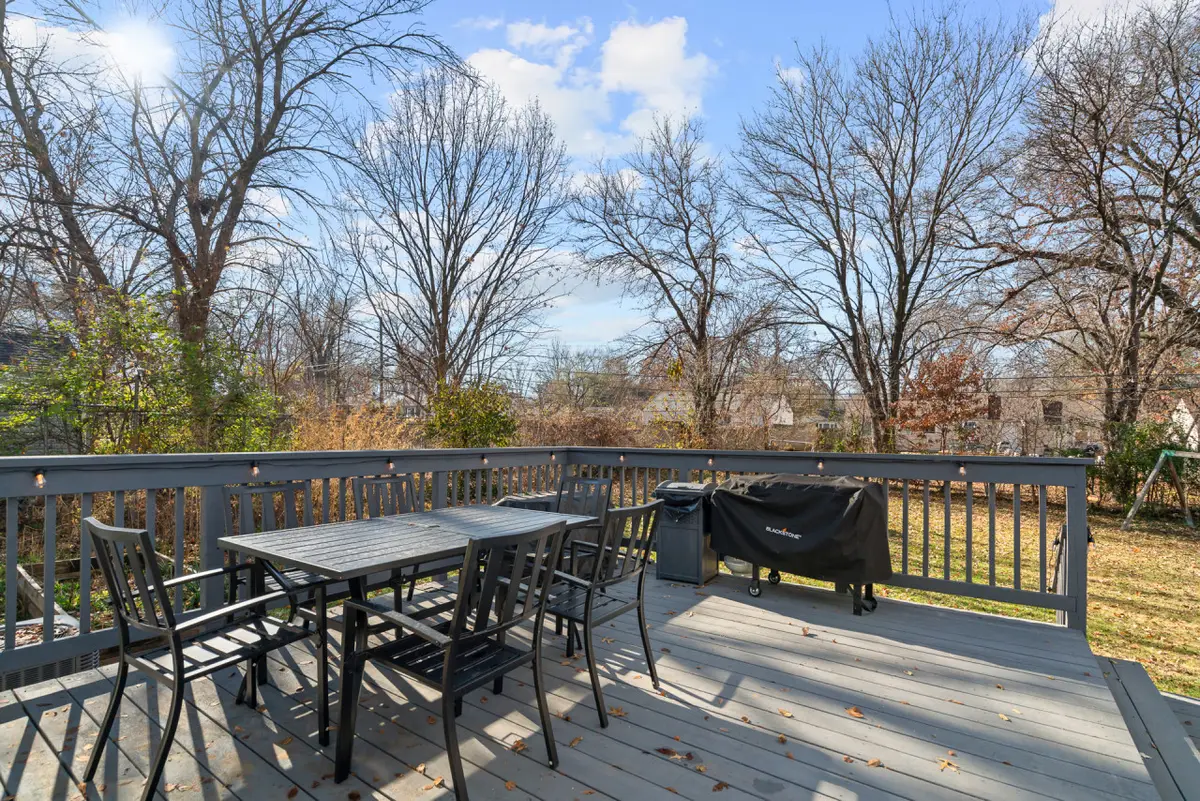 Deck with a dining table, chairs, and a covered grill, overlooking the backyard