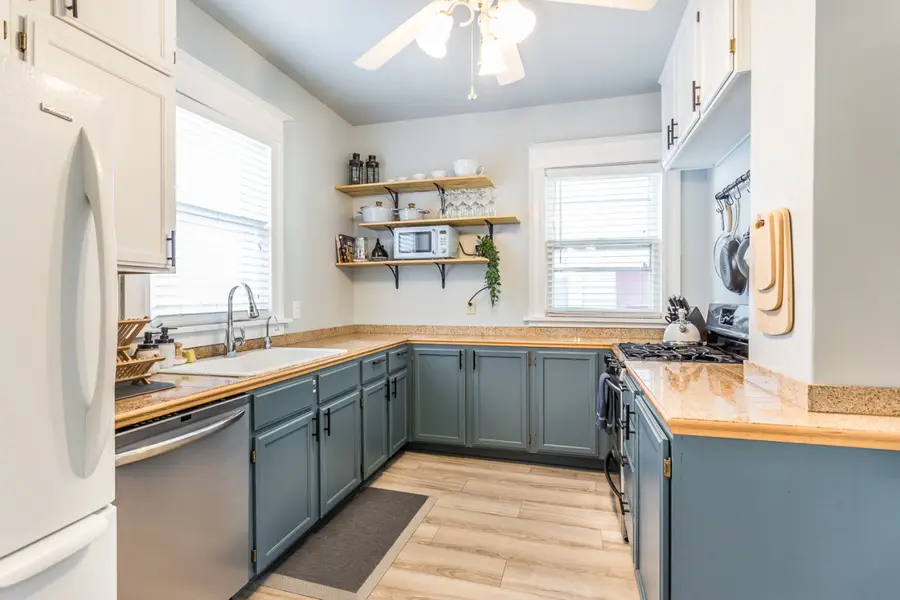 Kitchen with blue lower cabinets, butcher-block counters, and open shelves