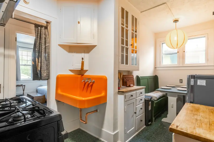 Kitchen with a gas range, an original orange farmhouse sink, and a green banquette nook