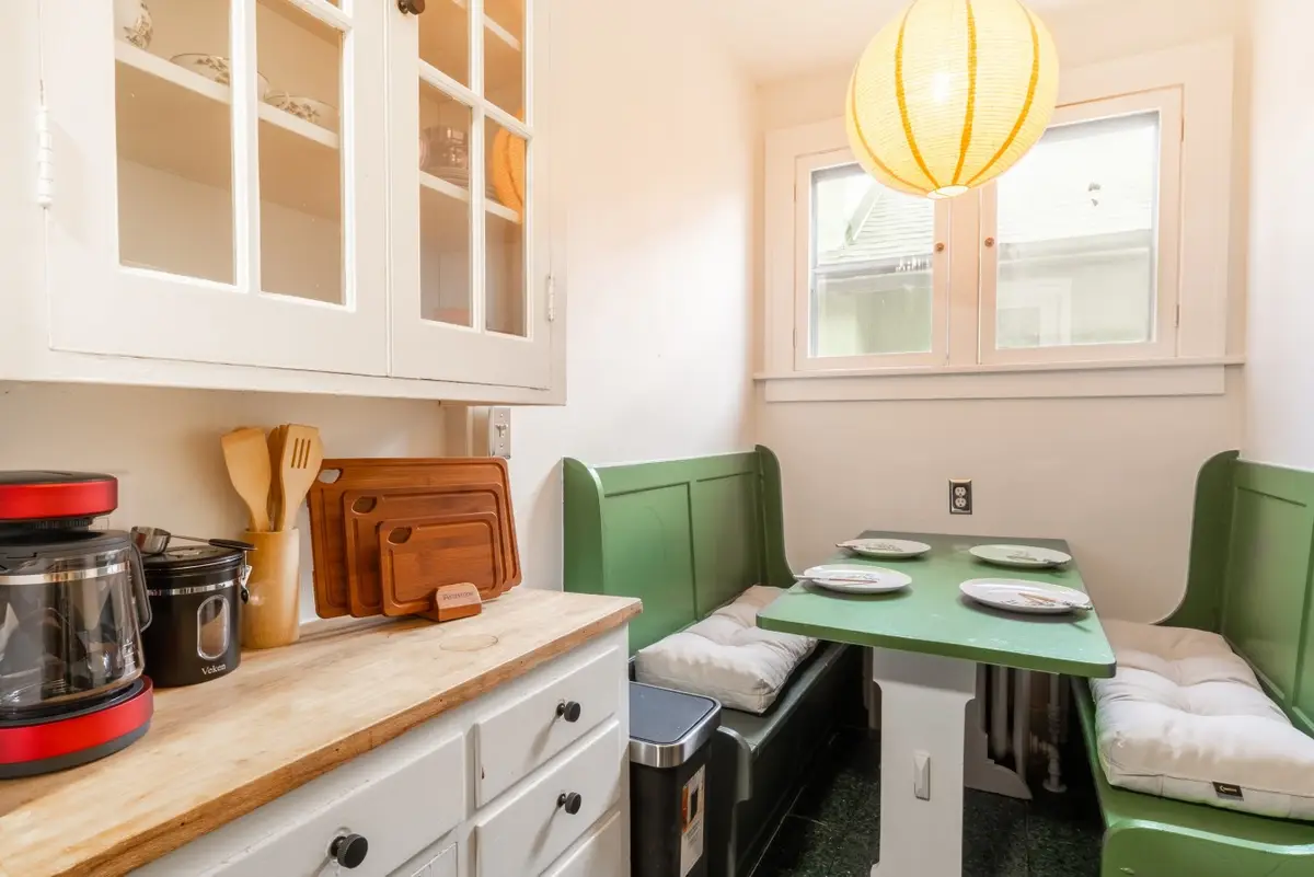 Breakfast nook with a green banquette, a paper lantern, and a coffee station