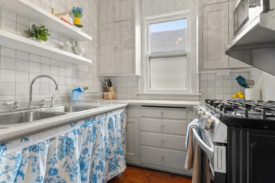 Kitchen with a floral-skirted double sink, open shelves, and a gas range