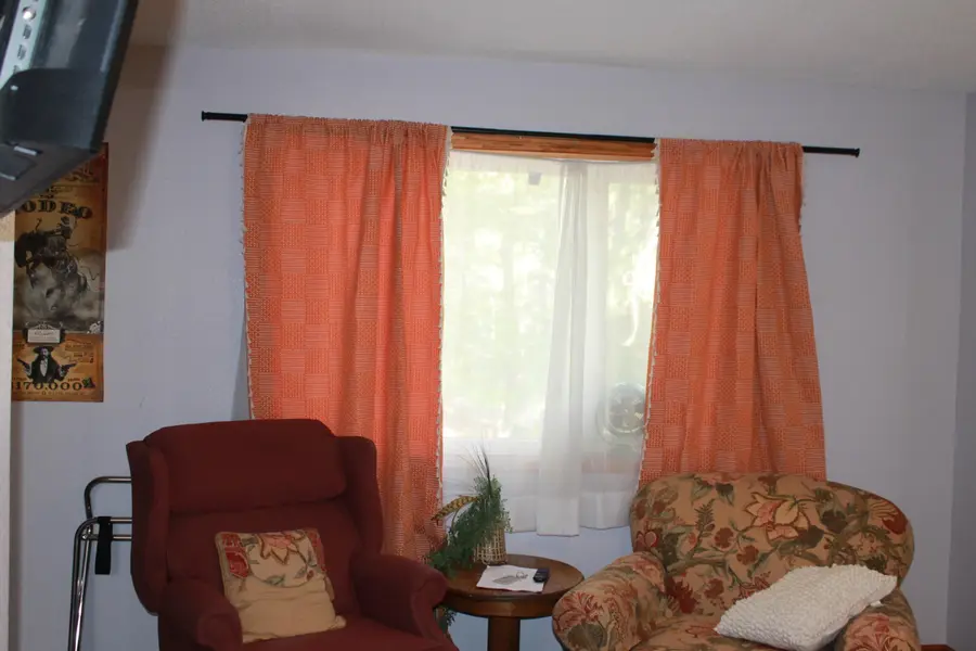 Sitting area with two armchairs by a window with orange curtains