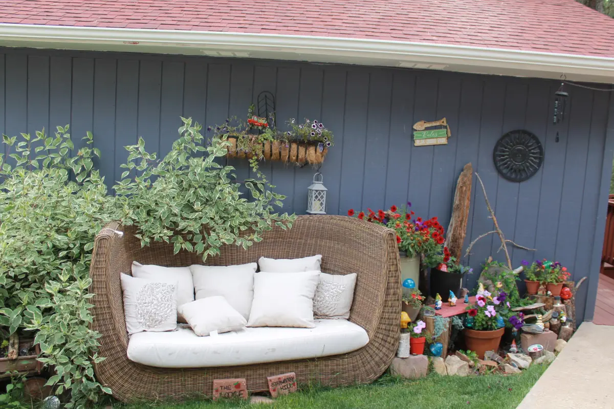 Wicker daybed with white cushions among the flowers