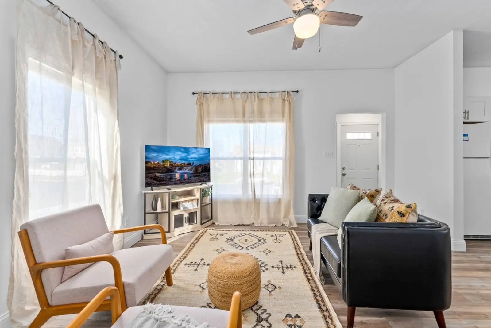 Living room with a leather sofa, two armchairs, and a TV by the window