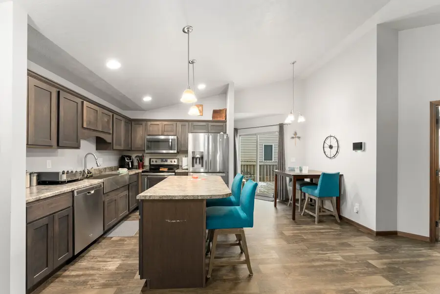 Kitchen with dark wood cabinets, stainless appliances, and teal stools at the island