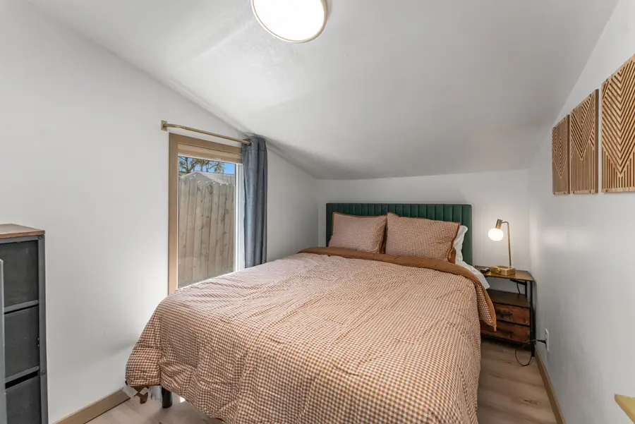 Bedroom with a green upholstered headboard, a patterned duvet, and a nightstand lamp