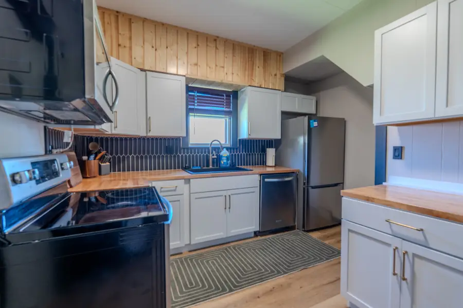 Kitchen with white cabinets, butcher-block counters, and a black range