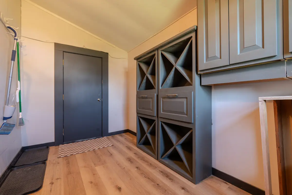 Mudroom with X-divided cubbies, drawers, and upper cabinets beside a dark door