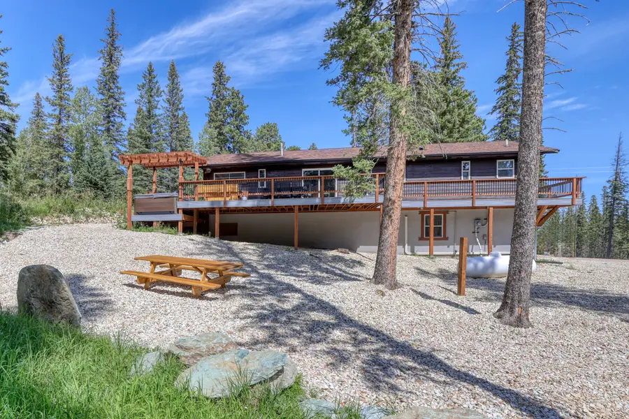 Whitetail & Spruce Hideaway from the back, with a long deck and pergola among the pines